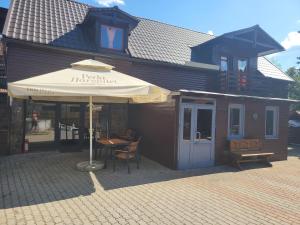 ein Gebäude mit einem Tisch und einem Sonnenschirm davor in der Unterkunft Morrison Apartments in Miercurea Ciuc
