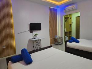 a room with two beds with blue chairs and a tv at Jade Resort - Bauang, La Union in Bauang