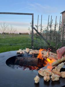 a person is cooking food on a grill at De Volle Maan - Lentehuis in Sint-Lievens-Houtem