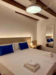 a bedroom with a large white bed with blue pillows at Hotel Casa Manolet 