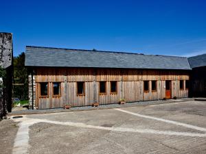 a wooden barn with a parking lot in front of it at Bluetit Cottage in Kings Nympton