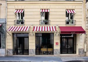 a building with red and white awnings and windows at Maison Honnel in Paris