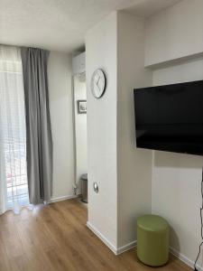 a living room with a clock on a wall with a tv at Apartment S&S Tomislavgrad in Tomislavgrad