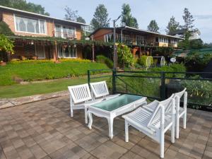 a patio with a table and two white chairs and a house at De Rock Jungle Living Resort in Coonoor