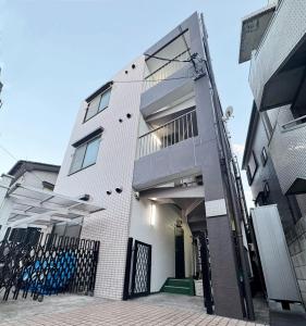 a white building with a gate in front of it at SnowMapleHouse川口 in Kawaguchi