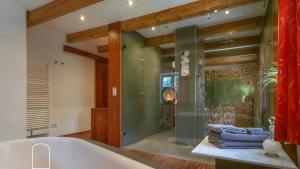 a bathroom with a tub and a glass shower at Exklusives Gut Stohrerhof am See in Dießen am Ammersee +37 photos