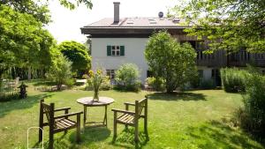 a table and two chairs in a yard with a building at Exklusives Gut Stohrerhof am See in Dießen am Ammersee