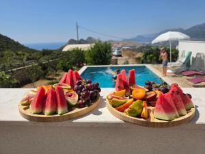 two plates of fruit on a table next to a pool at Apartments Nahla in Bar