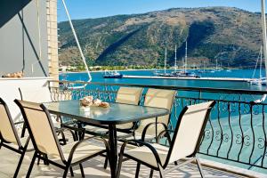 a table and chairs on a balcony with a view of the water at Vythos Occidens in Plataria
