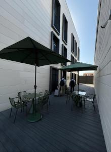 two tables and chairs with umbrellas on a deck at GAIA Hostel in Türkistan