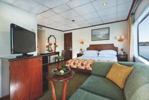a hotel room with a bed and a tv and a couch at Sun Nile Cruise in Aswan