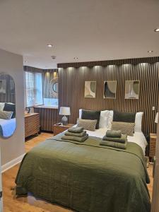 a bedroom with a large green bed with pillows at Old Sun Inn in Haworth