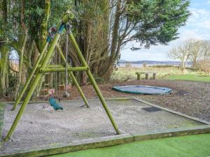 a swing set in a park with a trampoline at North Plain Barn in Bowness-on-Solway
