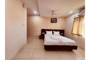a bedroom with a bed with white sheets and a window at FabHotel Udupi in Mysore