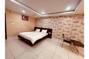 a bedroom with a bed and a chair in it at FabHotel Udupi in Mysore