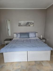 una camera da letto bianca con un grande letto con lenzuola blu di House Eifelglück a Großlittgen