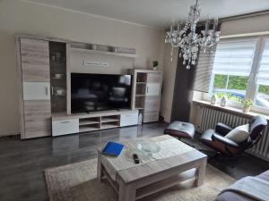 un soggiorno con televisore e tavolo di House Eifelglück a Großlittgen