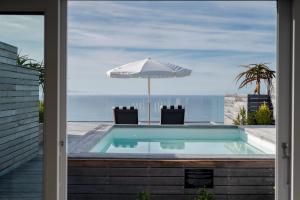 ein Swimmingpool mit Sonnenschirm und Meerblick in der Unterkunft Eleven in Plettenberg Bay