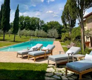 a group of lounge chairs next to a swimming pool at Podere San Pietro in Cetona