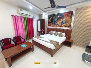 a bedroom with a bed and a table and a painting at hotel wisdom celebration in Motīhāri