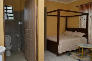 a bedroom with a four poster bed and a bathroom at Maria VillaSTUDIO2 in Voi