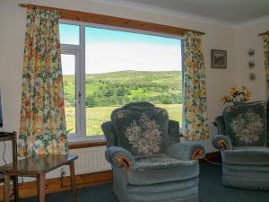 a living room with two chairs and a large window at Lower Brae in Achnahanat