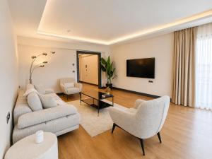 a living room with a couch and chairs and a tv at Utopia Suite Residence1 in Burunabat