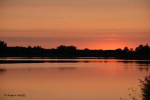 a sunset over a large body of water at Logis Hôtel Auberge de la Gabrière in Lingé +1 photo