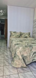 a bedroom with a bed with a comforter and pillows at Flat Centro Rota Cachoeira in Bonito