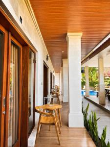a porch with a wooden ceiling and a table and chairs at Luling Guesthouse in Badung