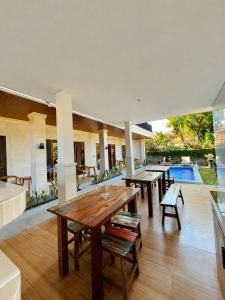 a patio with wooden tables and benches and a pool at Luling Guesthouse in Badung