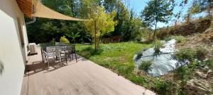 a deck with a table and chairs next to a river at Le gîte de Coline in La Bridoire +1 photo