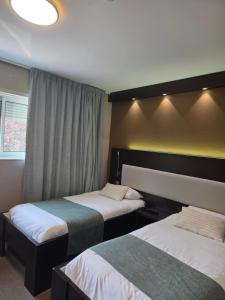 a hotel room with two beds and a window at Les Portes d'Apcher in Saint-Chély-dʼApcher