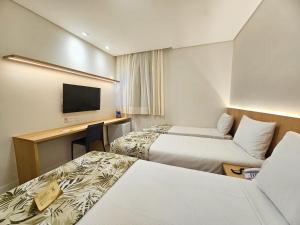 a hotel room with two beds and a desk at Opaba Praia Hotel in Ilhéus