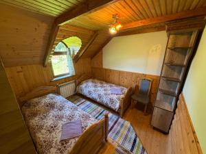 an attic room with two beds and a chair at Shelest Vody in Russkaya Mokraya