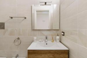 a bathroom with a white sink and a mirror at Maison Vivian Rooms in Marzamemi