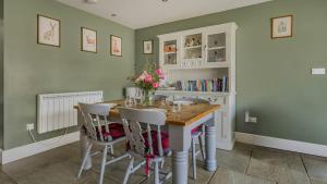 a dining room with green walls and a table with chairs at Roe Barn in Sherston +17 photos