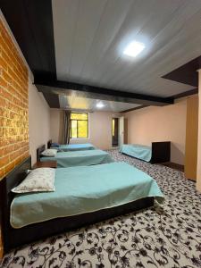 a room with four beds and a brick wall at Gostevoy dom Dovul in Chimgan