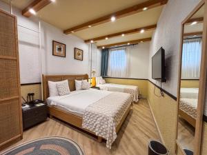 a bedroom with two beds and a television in it at Qara Otel in Ayvalık