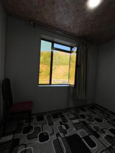 a room with a window and a chair and a carpet at Gostevoy dom Dovul in Chimgan