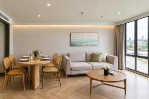 a living room with a couch and a table and chairs at The Quarter Chaophraya by UHG - Riverfront Hotel, Walk to ICONSIAM in Bangkok