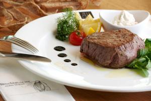 a steak on a plate with vegetables and a bowl of dip at Hotel Sachsenklemme in Fortezza