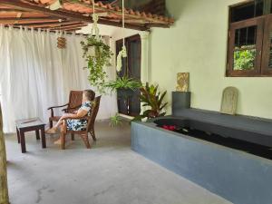 a woman sitting in a chair on a patio at Villa Lyvie ayurvedic hotel in Tangalle