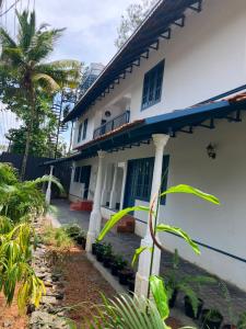 a white house with a palm tree in front of it at Aali villas in Mararikulam