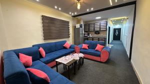 a living room with blue couches and red pillows at عجلون in Ajloun +2 photos