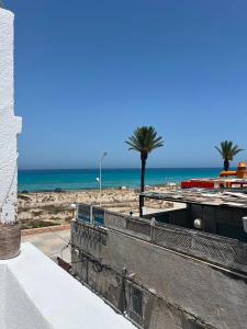 a view of a beach with palm trees and the ocean at Dar El corniche in Mahdia