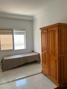a bedroom with a bed and a wooden cabinet at Dar El corniche in Mahdia
