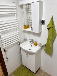 a white bathroom with a sink and a mirror at Urban Taft Stay Skopje-Modern Vodno View Suite with Private Parking in Taftalidze in Skopje
