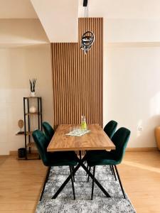 a dining room with a wooden table and green chairs at Urban Taft Stay Skopje-Modern Vodno View Suite with Private Parking in Taftalidze in Skopje +24 photos