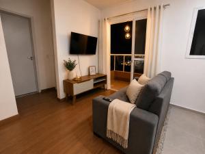 a living room with a couch and a television at Flat Terras de Portinari in Barretos